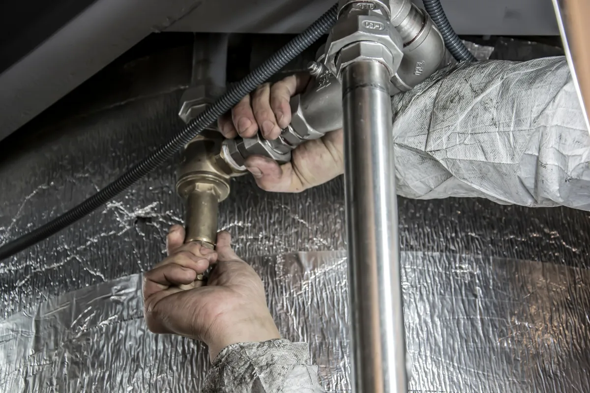 Gas union and isolation valve being checked by hand during a gas geyser repair callout